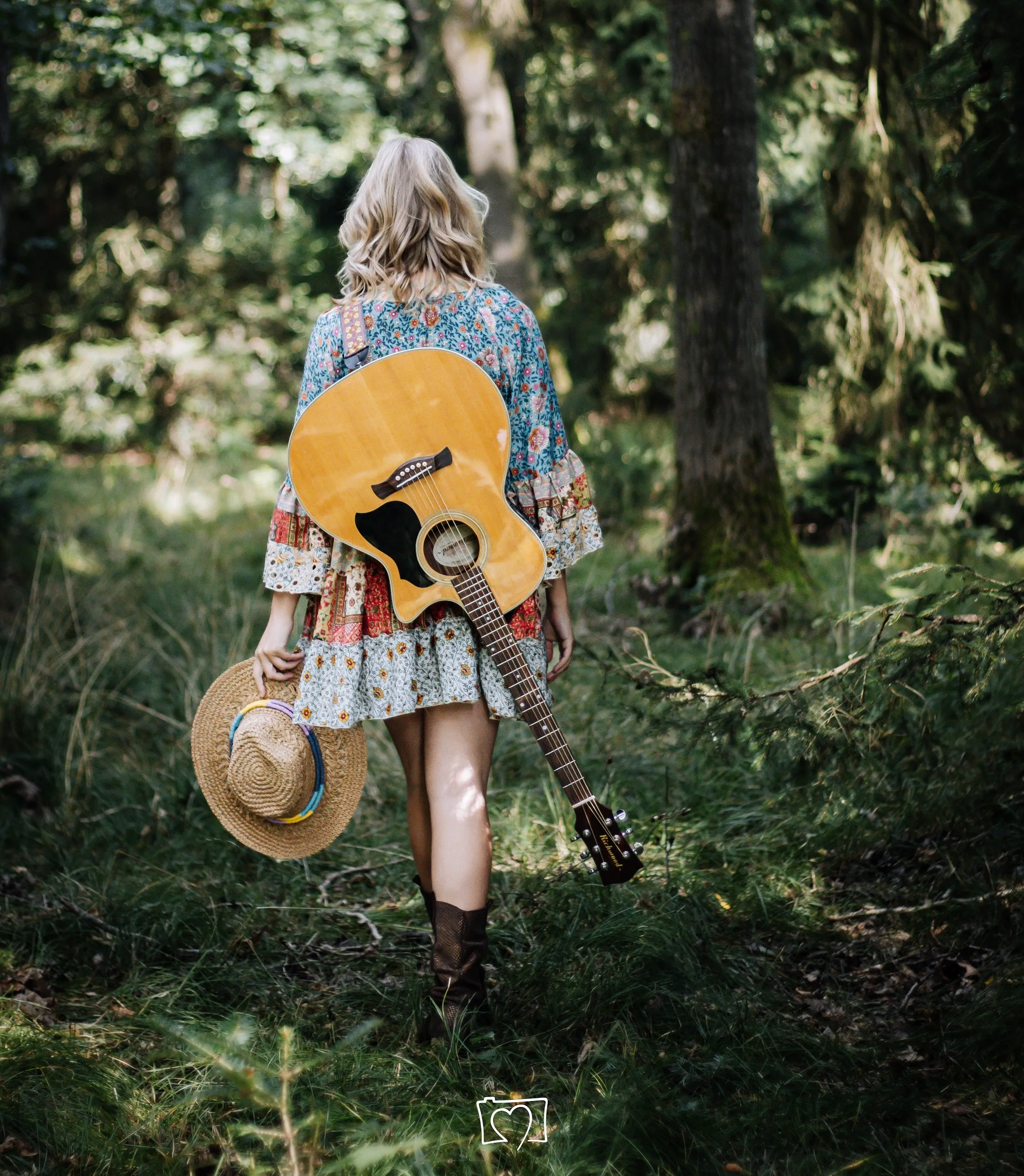 Katharina Wutz mit Gitarre und Hut in einem Wald